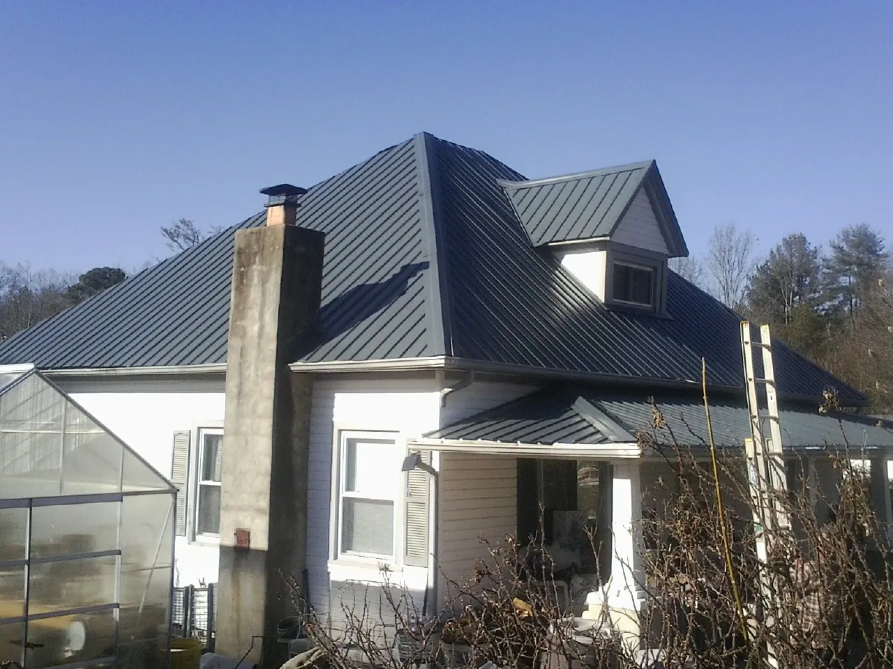 Dark blue standing seam metal roof on a white farmhouse with dormer — Slate & Tile Roof Repair by Roofing Brothers in South Park