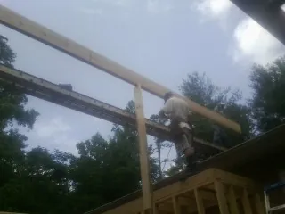 Carpenter setting a ridge beam over a new addition frame — Ice Dam Removal by Roofing Brothers in South Park