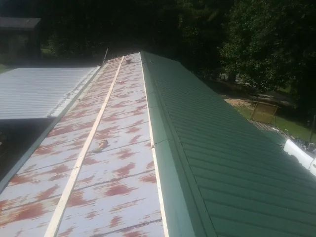 Old rusted panels beside newly installed green metal roofing — Wind Damage Roof Repair by Roofing Brothers in South Park