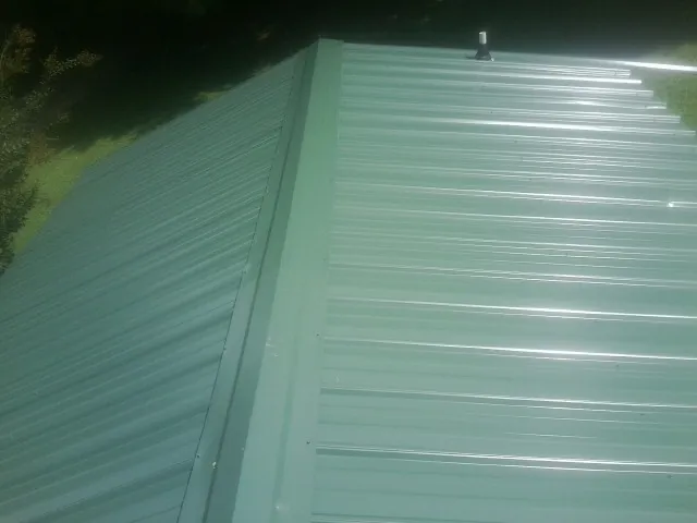New green metal panels meeting at the ridge of a roof — Flat Roof Repair work by our crew in South Park