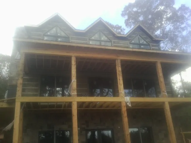 Dormers and porch framing on a large log home under construction — Roof Coating work by our crew in South Park