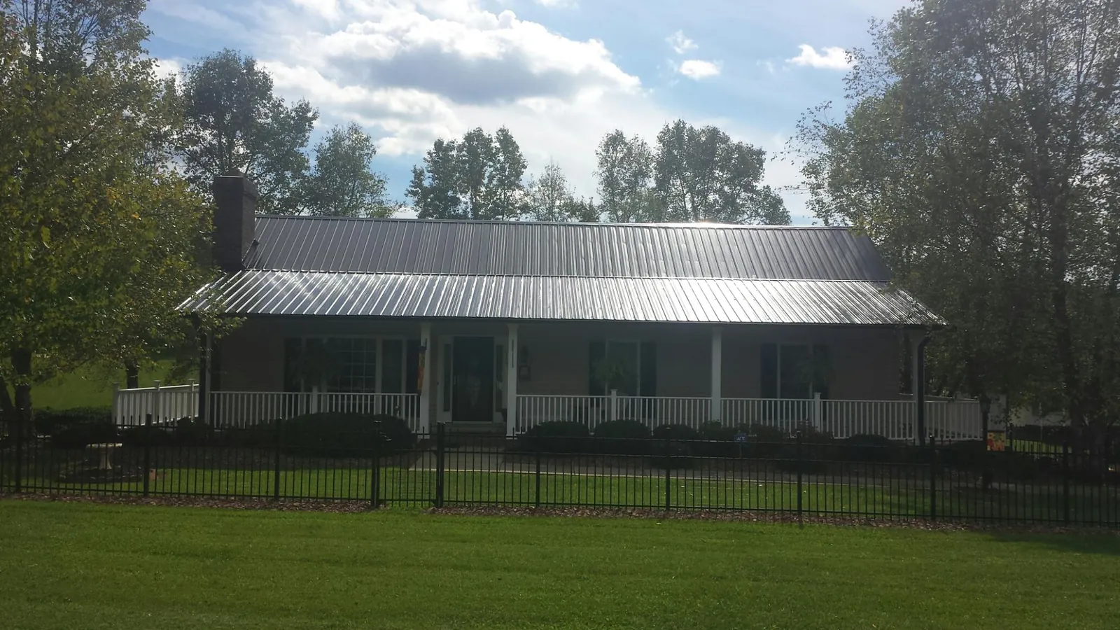 Gray metal roof on a brick ranch with a full width front porch — Gutter Guard Installation work by our crew in South Park