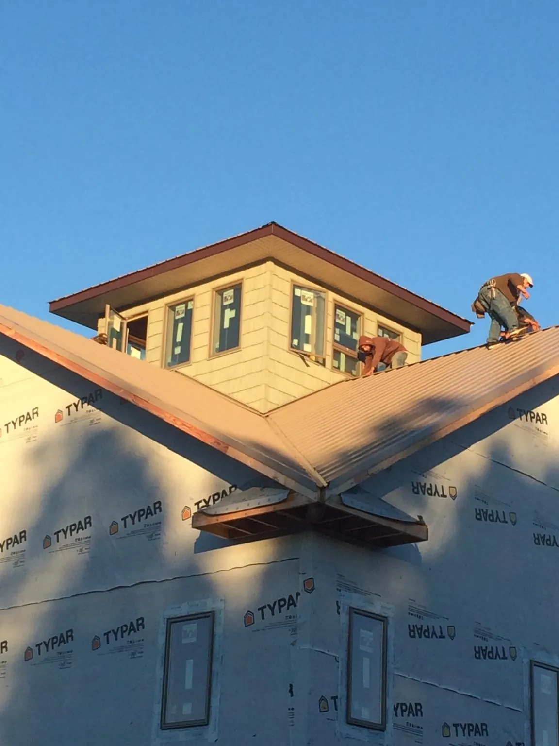Roofers working around a rooftop cupola on a new metal roof at sunset — Roof Waterproofing in South Park by Roofing Brothers